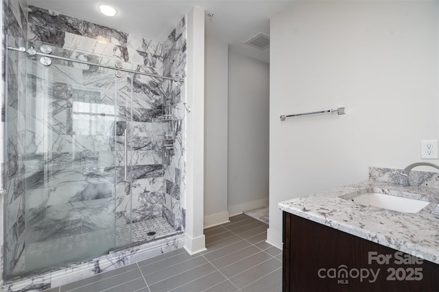 bathroom featuring vanity, tile patterned floors, baseboards, visible vents, and a stall shower