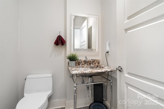 bathroom with toilet, baseboards, and a sink