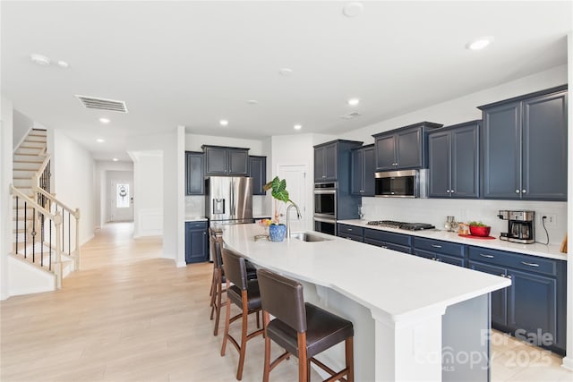 4069 Havenport Cir, Tega Cay, SC 29708 - kitchen featuring appliances with stainless steel finishes, a kitchen bar, a kitchen island with sink, tasteful backsplash, and light wood-style floors