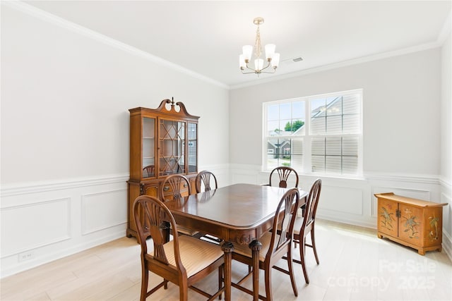 4069 Havenport Cir, Tega Cay, SC 29708 - dining space featuring a chandelier, light wood-type flooring, a wainscoted wall, ornamental molding, and a decorative wall