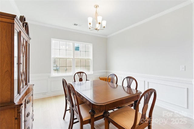 4069 Havenport Cir, Tega Cay, SC 29708 - dining space with a chandelier, ornamental molding, a wainscoted wall, and light wood-style flooring