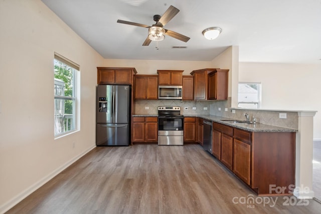 1175 Valley St Unit 111, Statesville, NC 28677 - kitchen with a sink, brown cabinetry, light wood-type flooring, appliances with stainless steel finishes, and decorative backsplash