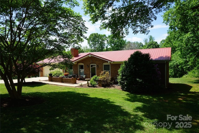 view of front of house featuring a garage, a chimney, metal roof, and a front lawn
