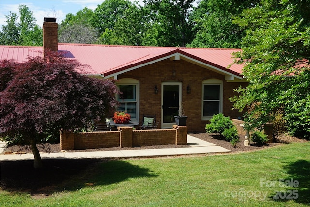 view of front of house with a front lawn, a chimney, and metal roof