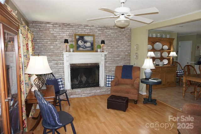 living area featuring a ceiling fan, wood finished floors, and a fireplace