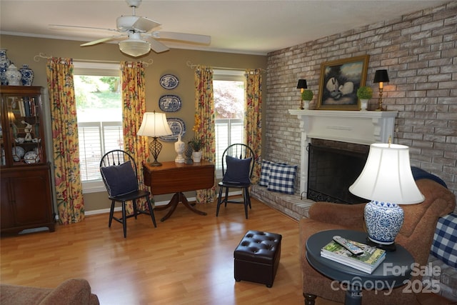 interior space featuring plenty of natural light, a ceiling fan, wood finished floors, and a brick fireplace