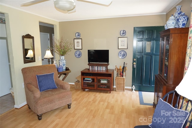 living room with crown molding, ceiling fan, baseboards, and wood finished floors