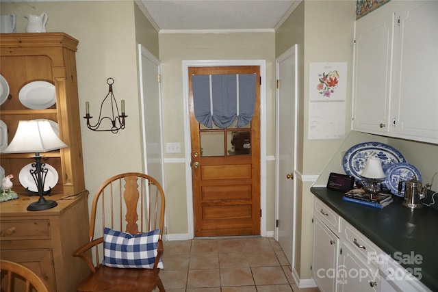entryway featuring baseboards, ornamental molding, and light tile patterned flooring