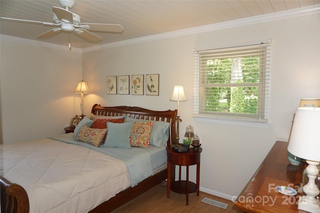 bedroom with crown molding, baseboards, wood finished floors, and visible vents