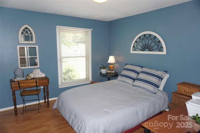 bedroom featuring baseboards, multiple windows, and wood finished floors