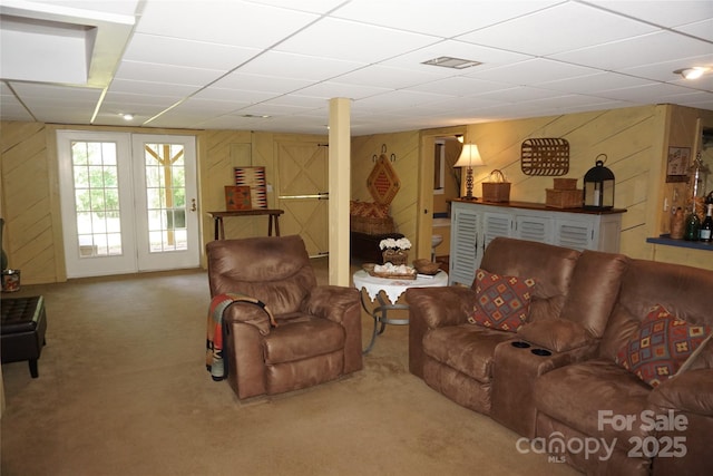 living room with carpet floors, wood walls, and a drop ceiling