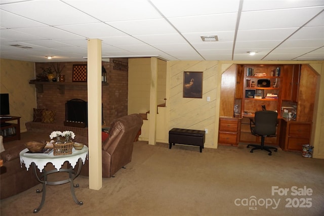 living room with light colored carpet, a drop ceiling, visible vents, and a fireplace