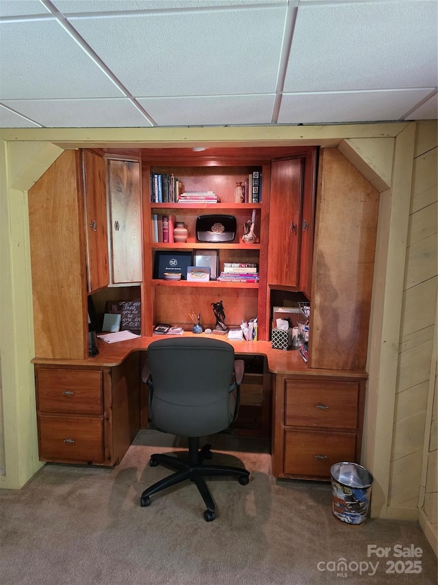 home office featuring carpet, built in desk, and a drop ceiling