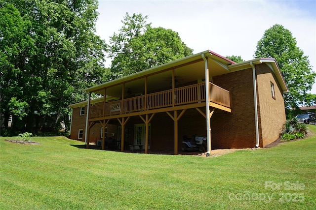 rear view of house featuring brick siding, a ceiling fan, a yard, and a deck