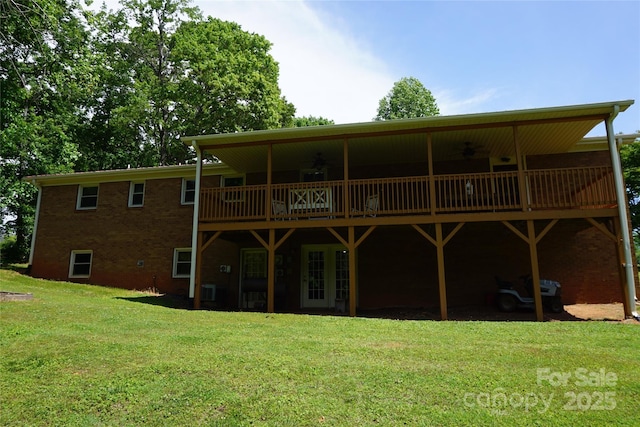 back of property with a lawn, a deck, ceiling fan, and brick siding