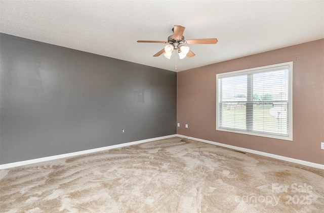carpeted spare room featuring a ceiling fan and baseboards