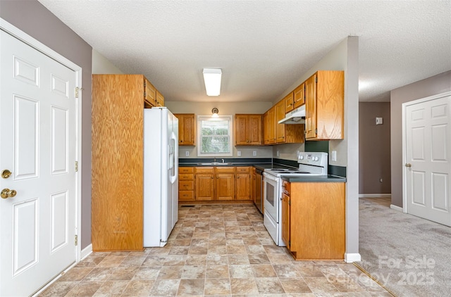 kitchen featuring dark countertops, white appliances, baseboards, under cabinet range hood, and a sink