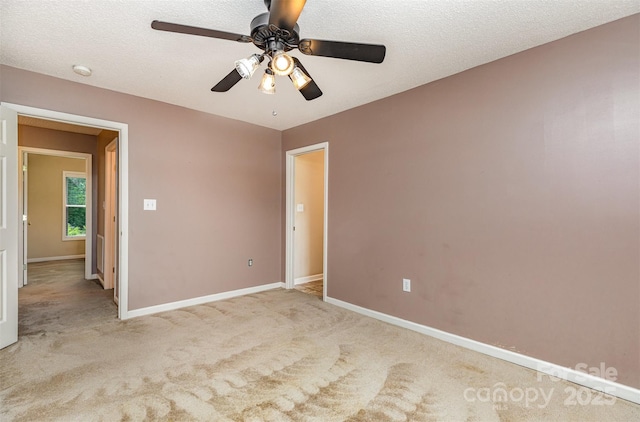 carpeted spare room with a textured ceiling, ceiling fan, and baseboards