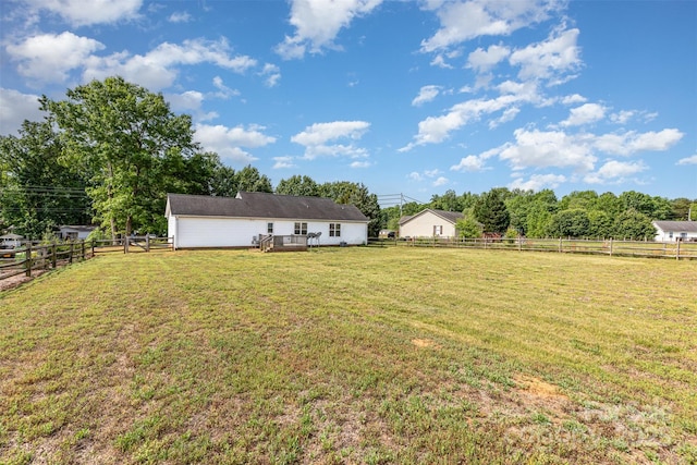 view of yard with a rural view, a wooden deck, and a fenced backyard