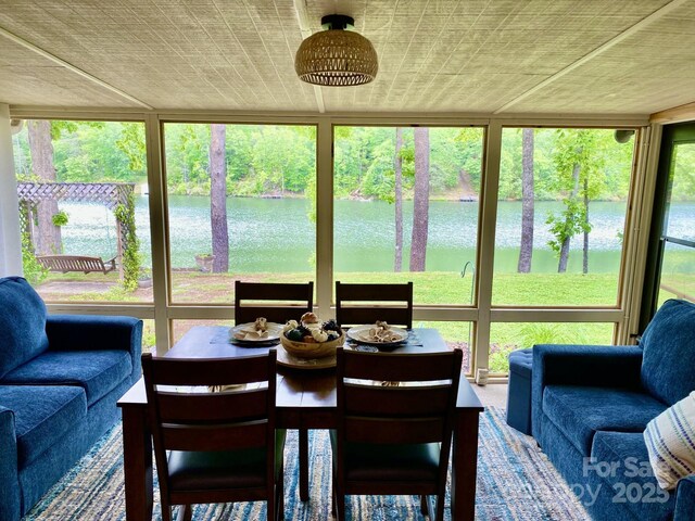 sunroom / solarium with a water view and view of scattered trees