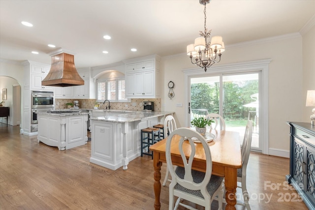 12048 Royal Portrush Dr, Charlotte, NC 28277 - dining area with crown molding, arched walkways, an inviting chandelier, recessed lighting, and light wood-style flooring