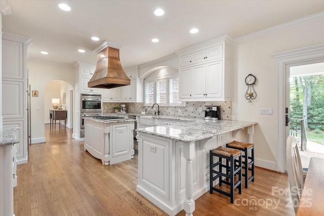 12048 Royal Portrush Dr, Charlotte, NC 28277 - kitchen with white cabinets, double oven, arched walkways, island exhaust hood, and backsplash
