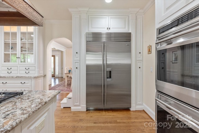 12048 Royal Portrush Dr, Charlotte, NC 28277 - kitchen with appliances with stainless steel finishes, light wood-type flooring, arched walkways, and white cabinetry
