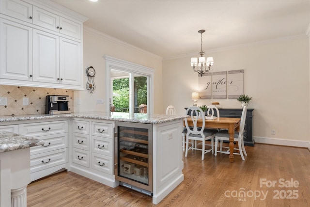 12048 Royal Portrush Dr, Charlotte, NC 28277 - kitchen featuring an inviting chandelier, light wood-style flooring, white cabinetry, and wine cooler