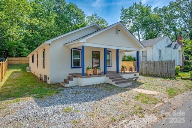 bungalow-style home featuring covered porch, fence, and stucco siding