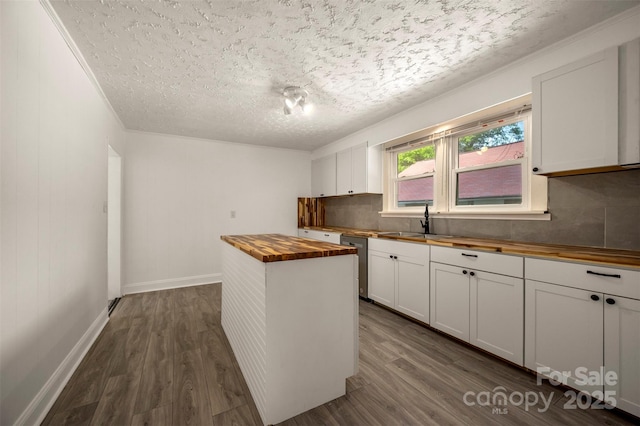 kitchen featuring decorative backsplash, a textured ceiling, dark wood finished floors, a sink, and wood counters