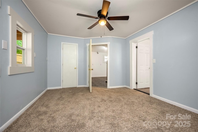 unfurnished bedroom featuring carpet floors, a ceiling fan, baseboards, and ornamental molding