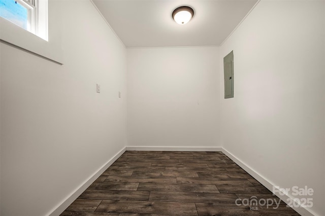 empty room featuring baseboards, ornamental molding, electric panel, and dark wood-style floors