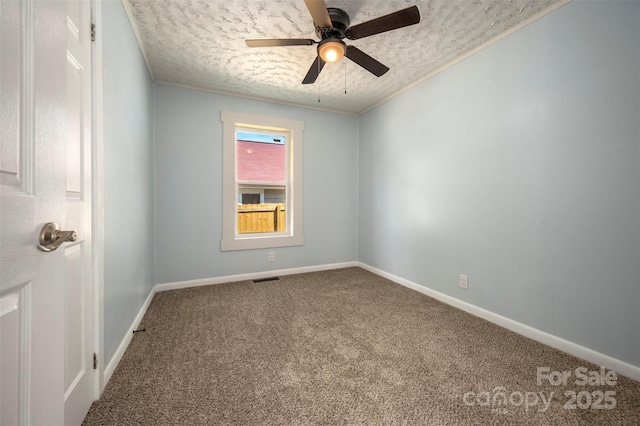empty room featuring a ceiling fan, a textured ceiling, baseboards, ornamental molding, and carpet