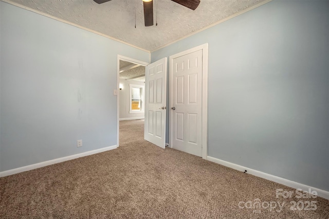interior space featuring carpet floors, ornamental molding, a textured ceiling, and baseboards