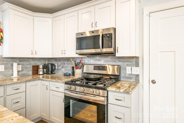 4838 Holbrook Dr, Charlotte, NC 28212 - kitchen with appliances with stainless steel finishes, tasteful backsplash, white cabinetry, and light stone countertops