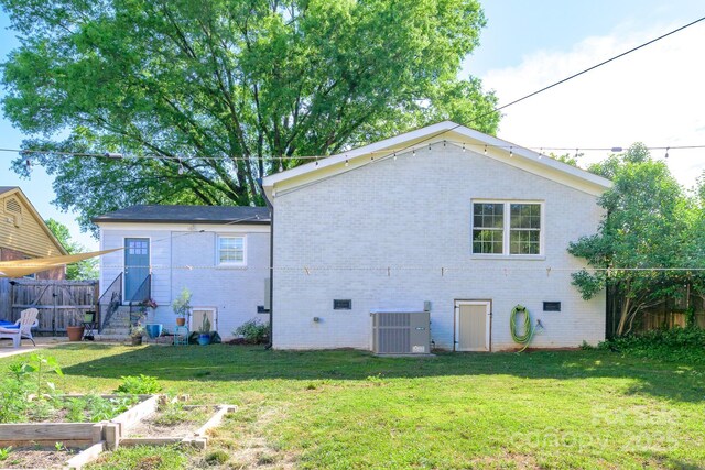 4838 Holbrook Dr, Charlotte, NC 28212 - back of property featuring brick siding, central AC, and a vegetable garden