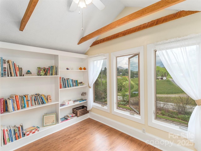sitting room featuring ceiling fan, wood finished floors, and vaulted ceiling with beams