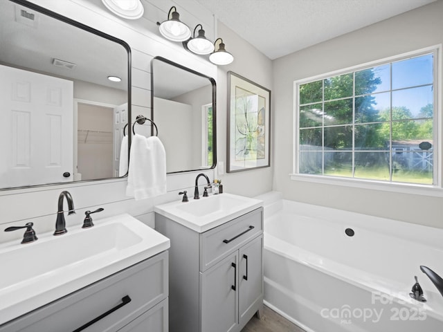 4101 New Castle Ln, Monroe, NC 28110 - full bath featuring healthy amount of natural light, two vanities, a bath, and a textured ceiling