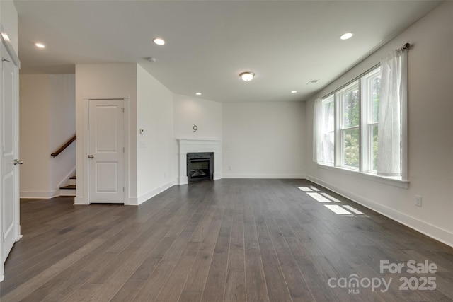 unfurnished living room featuring dark wood-style flooring, stairs, a fireplace, baseboards, and recessed lighting