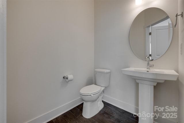 bathroom featuring baseboards, toilet, and wood finished floors