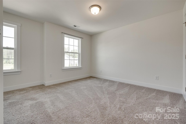 empty room featuring baseboards, visible vents, and light colored carpet