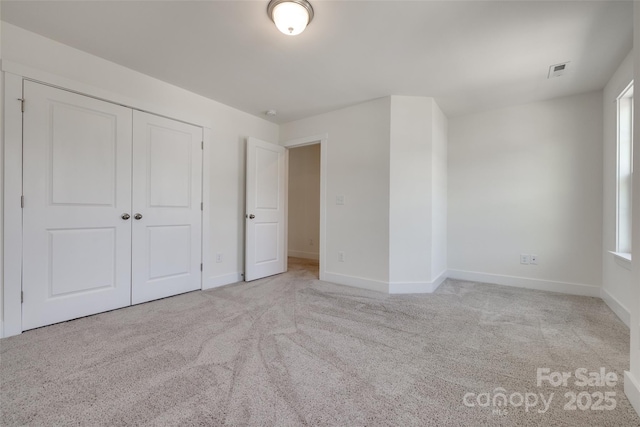 unfurnished bedroom featuring carpet floors, baseboards, visible vents, and a closet