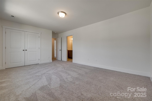 unfurnished bedroom featuring baseboards, a closet, and light carpet