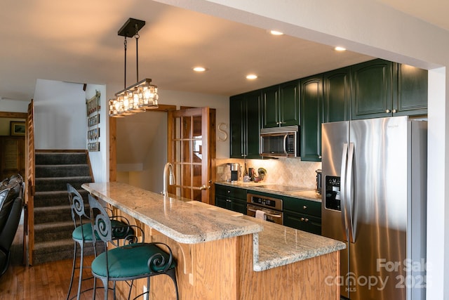 kitchen with appliances with stainless steel finishes, green cabinets, recessed lighting, light stone counters, and dark wood-style floors