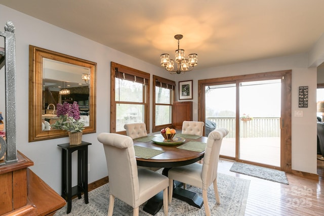 dining space with a chandelier, healthy amount of natural light, light wood-style floors, and baseboards