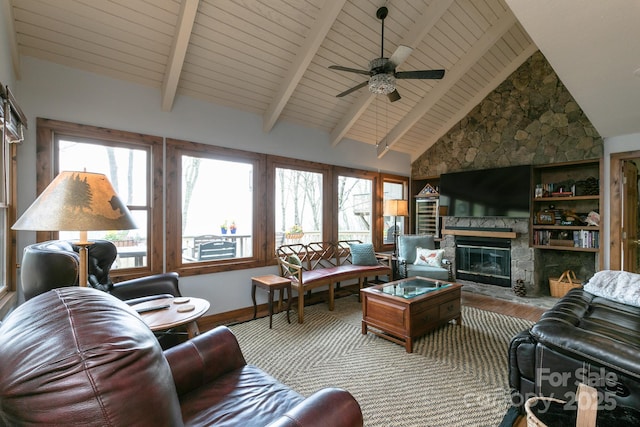 living room with wood finished floors, ceiling fan, a stone fireplace, beamed ceiling, and baseboards