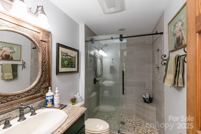 bathroom with a stall shower, vanity, and toilet