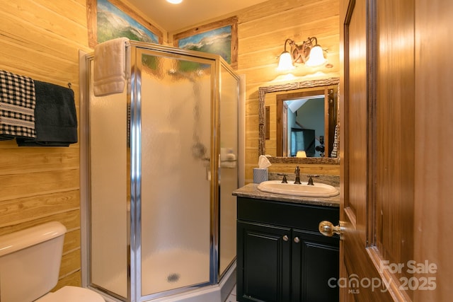 bathroom featuring wood walls, a stall shower, vanity, and toilet