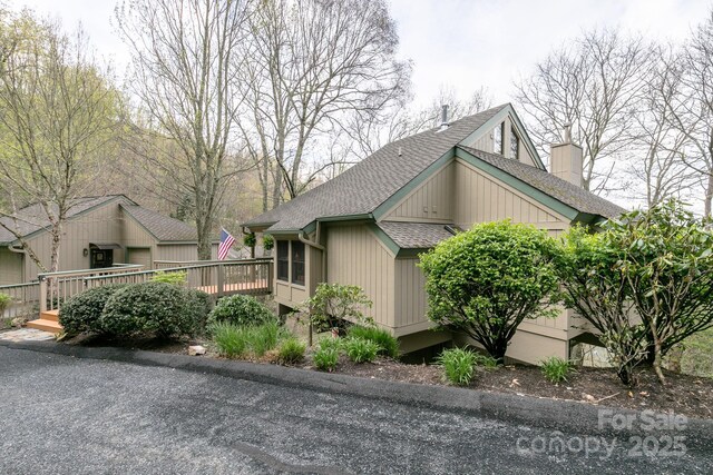 view of property exterior featuring a shingled roof, a wooden deck, and a chimney