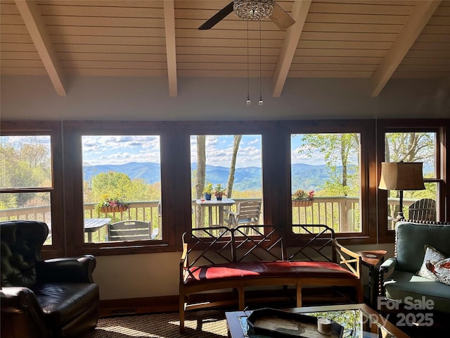sunroom / solarium with beam ceiling, a mountain view, baseboards, and wooden ceiling